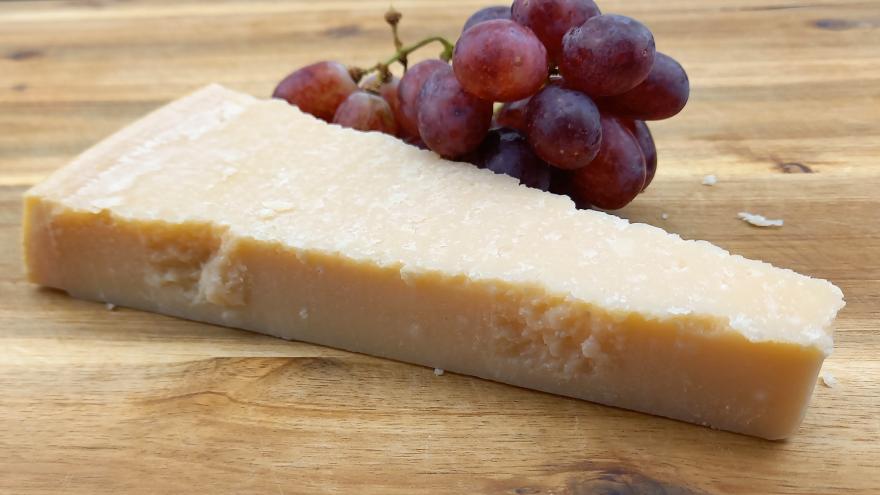 Stück Parmesan mit blauen Trauben auf Holzbrett