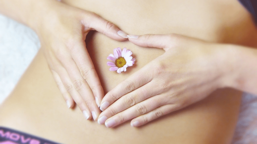 Eine junge Frau hält sich die Hände entspannt vor den Bauch.