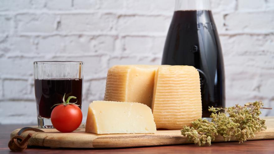 Auf einem Tisch stehen mehrere Lebensmittel, die Histamine enthalten - unter anderem Käse und eine Tomate.
