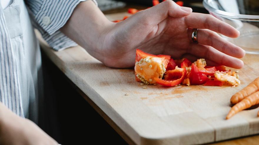 Abschnitte einer Paprika werden von einem Schneidebrett geschoben