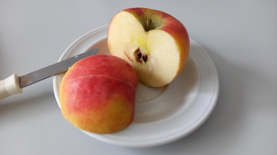 In Hälften geschnittener roter Apfel auf weißem Teller