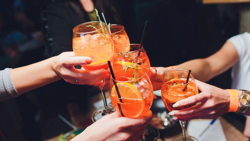 Foto von fünf Händen mit Aperol-Gläsern, die anstoßen
