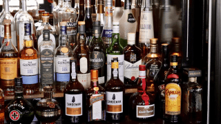 Mehrere Flaschen Alkohol stehen in einer Bar nebeneinander.