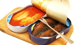 Geöffnete Heringsfiletdosen und Besteck.