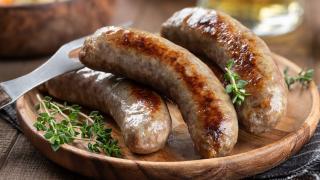 Gegrillte Bratwürste liegen garniert mit Thymian auf