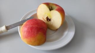 In Hälften geschnittener roter Apfel auf weißem Teller