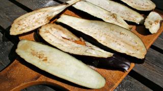 Auberginenscheiben und Salz auf einem Brett.