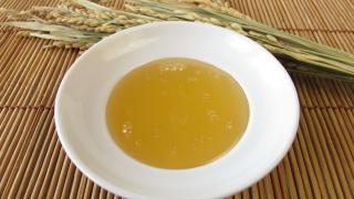 Reissirup in einer Schüssel neben einer Reisrispe.