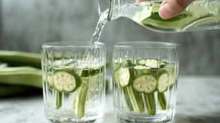 Jemand schüttet Okrawasser in zwei Gläser ein