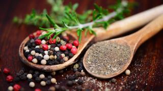 Verschieden gemahlene Pfefferkörner auf zwei Holzlöffeln